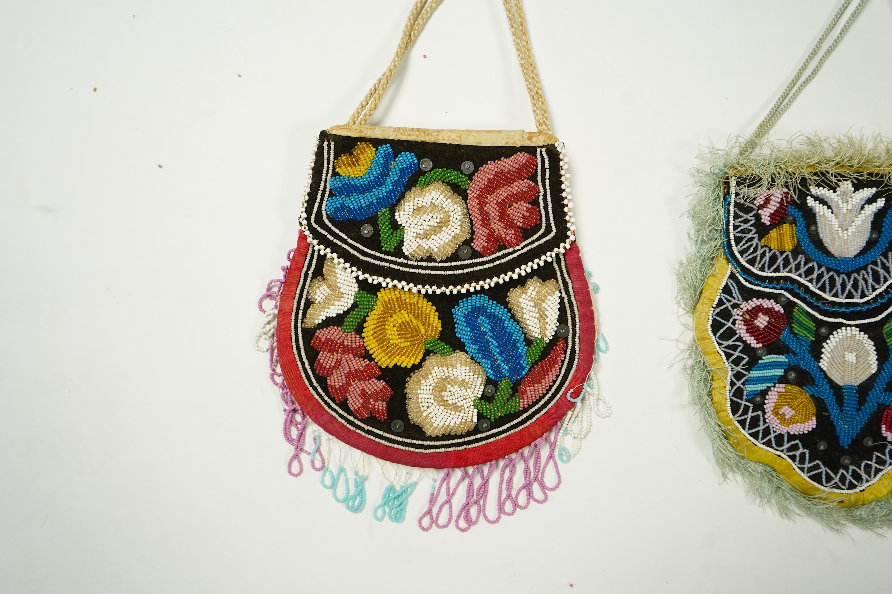Two Native American Iroquois beaded bags. One edged with fine pale blue silk fringing, the other larger with bead worked fringing. Largest 16.5cm high. Condition - The blue fringed bag has a few sequins missing and the f